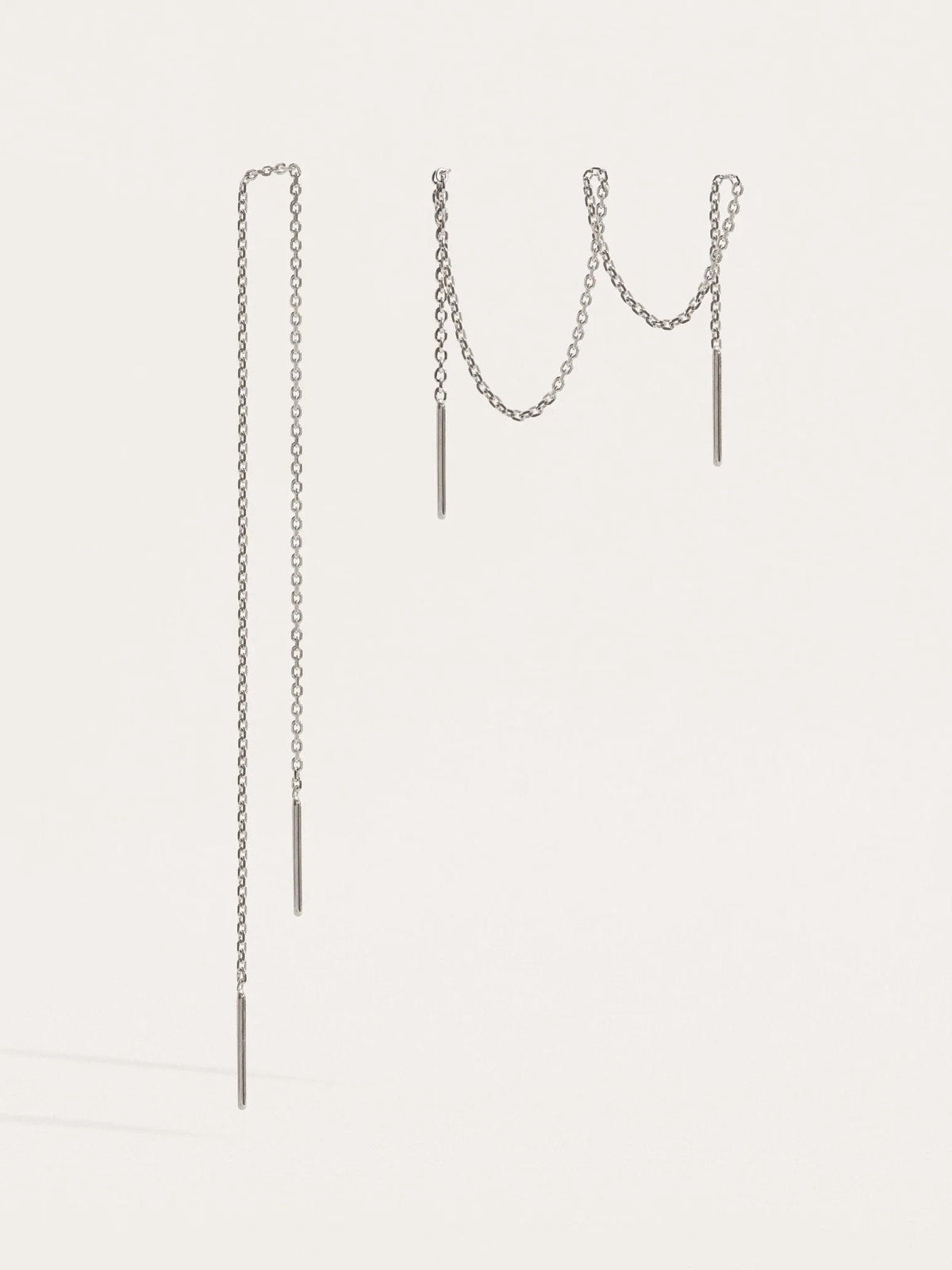 Pair of 925 sterling silver ear thread earrings in two different lengths, with fine chain and small bar ends, on a light background