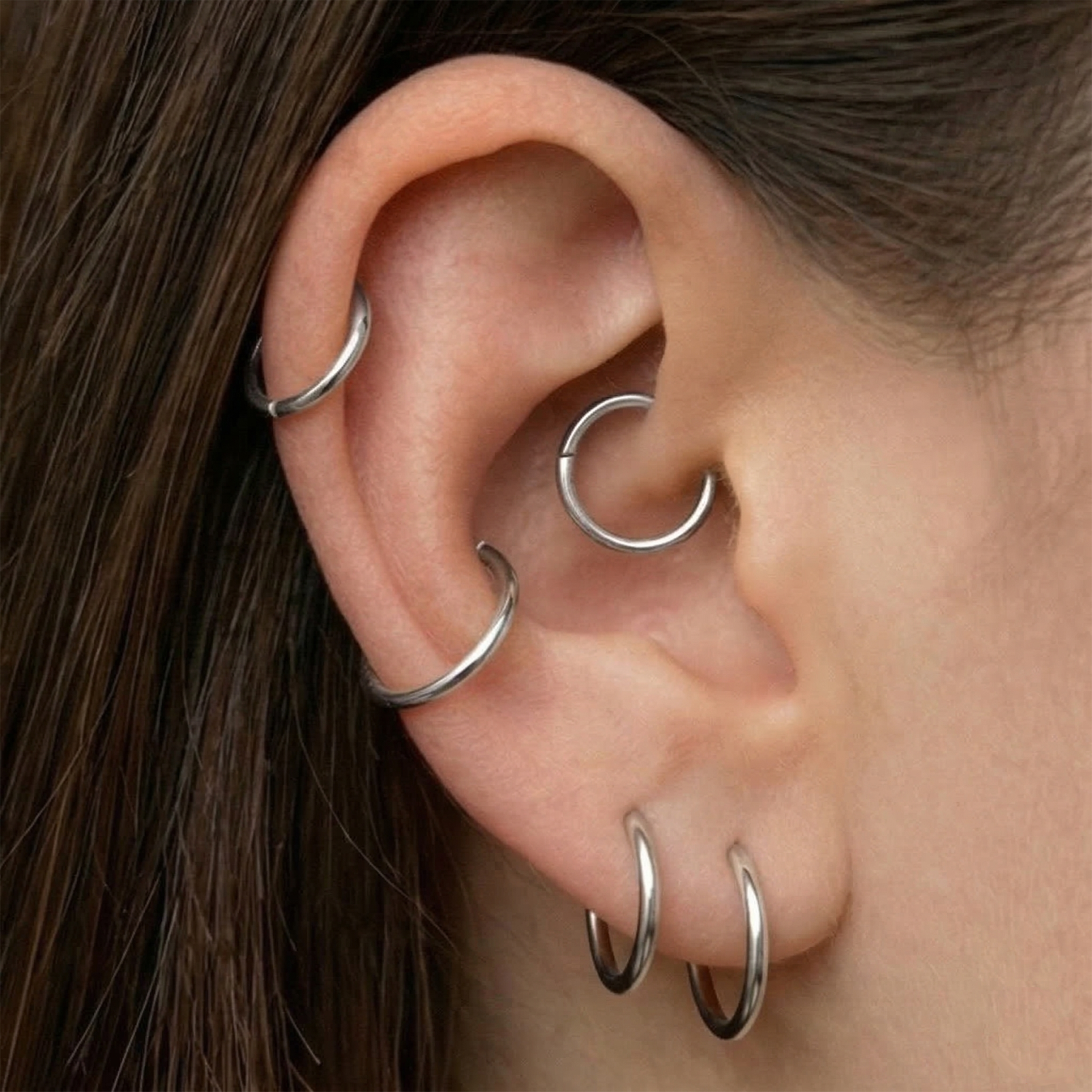 Silver hinged hoop shown on ear with helix and lobe piercings
