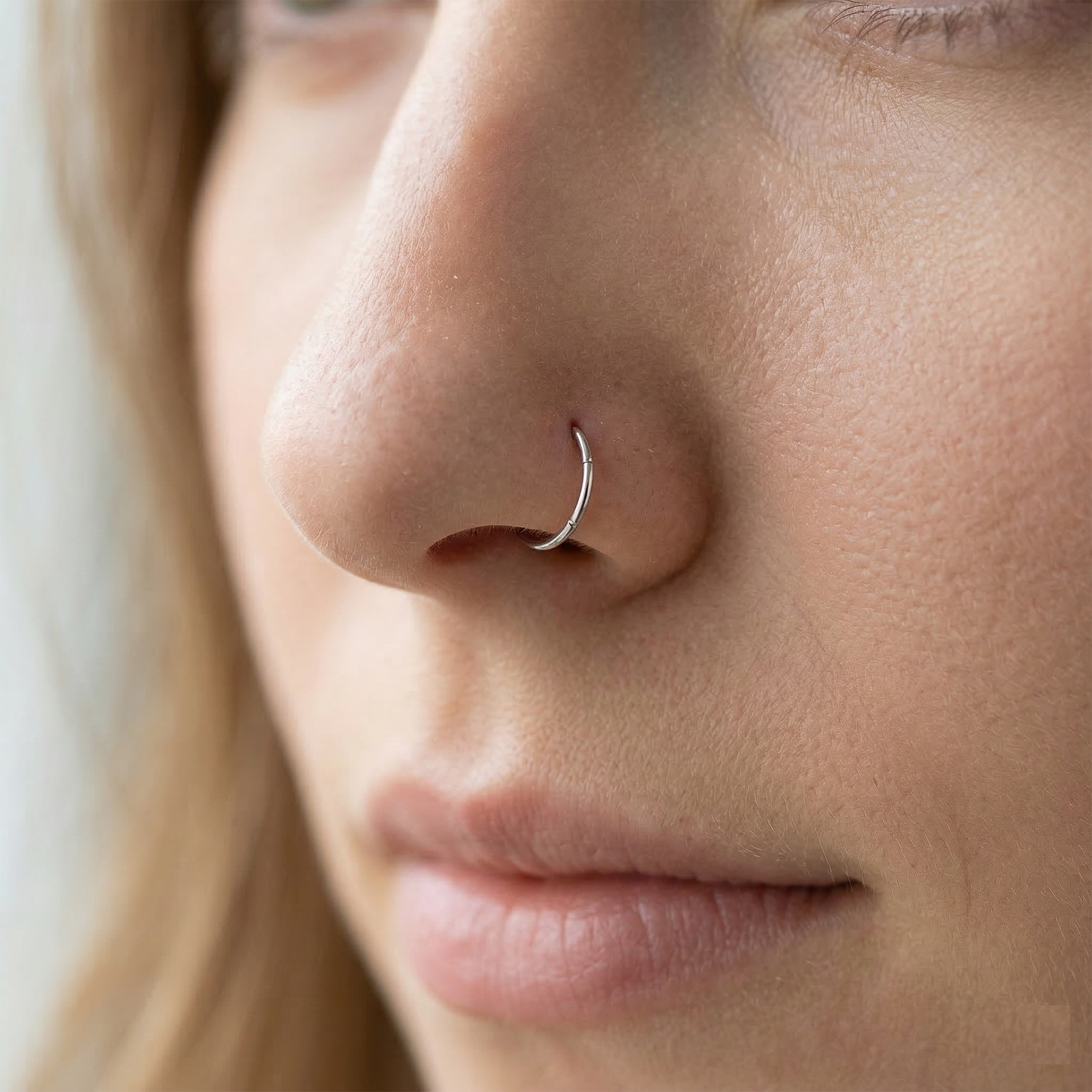 Silver hinged hoop shown on nostril piercing