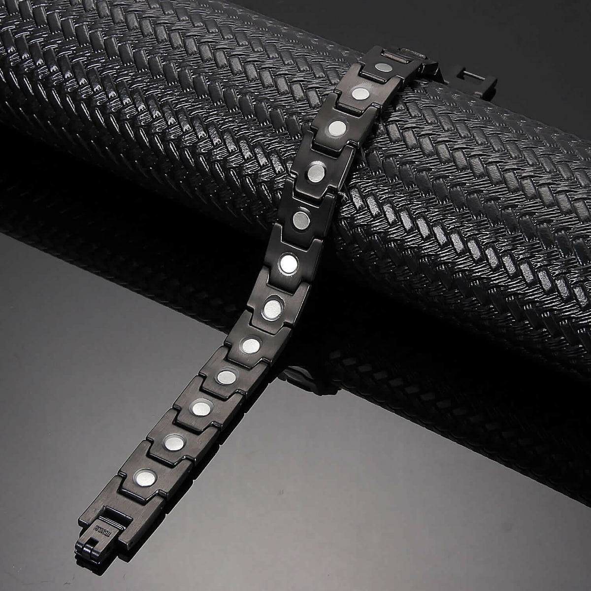 Melchior Jewellery black titanium magnetic bracelet for women displayed on textured black surface with link design and magnets
